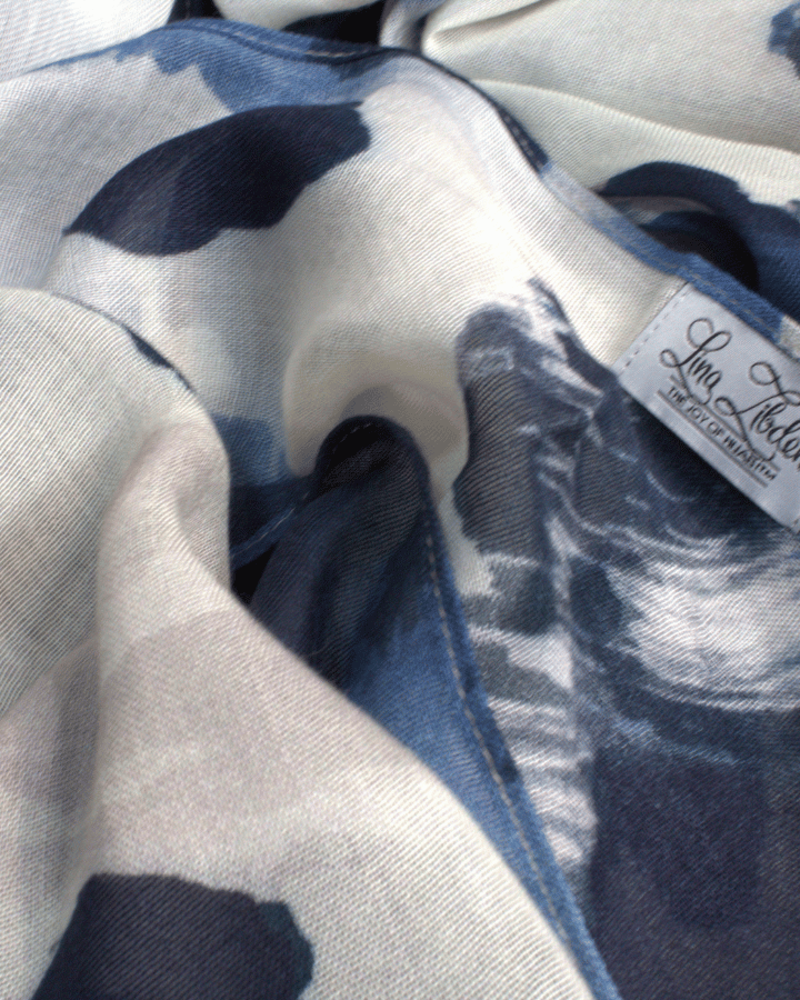 Close-up of a fabric with blue, black and beige leopard pattern hijab scarf and a visible label.