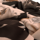 Close-up of floral details on a luxurious white scarf, featuring golden and silver strokes.