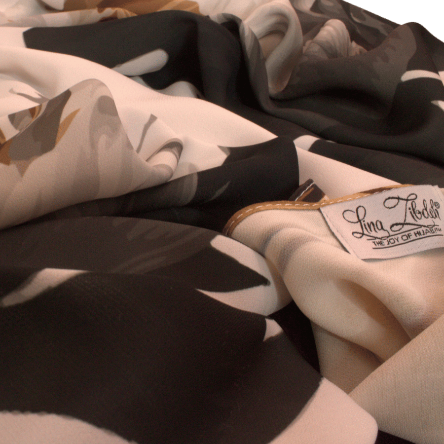 Close-up of floral details on a luxurious white scarf, featuring golden and silver strokes.