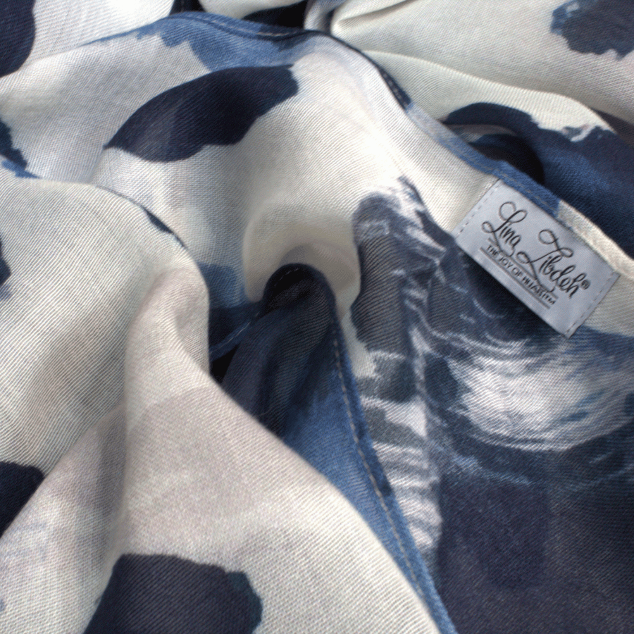 Close-up of a fabric with blue, black and beige leopard pattern hijab scarf and a visible label.